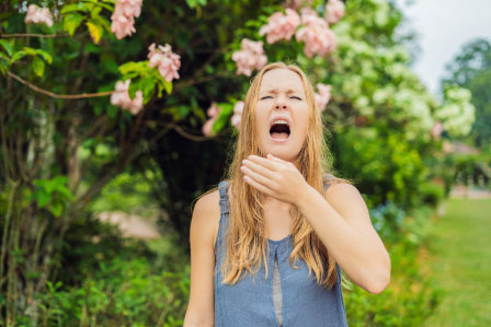 girl sneezing outside due to allergies